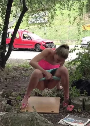 Босоногая девушка Рита приседает на корточки перед тем, как помочиться в воду