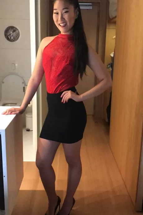 Азиатка в черной мини-юбке раздевается перед сексом от первого лица на кровати