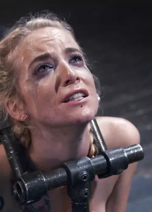 Одетая женщина с темными волосами пытает связанную женщину горячим воском