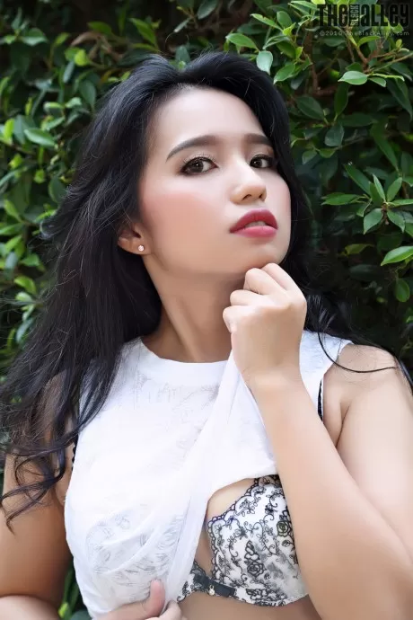 Красивая азиатка Нора полностью раздевается рядом с живой изгородью в саду