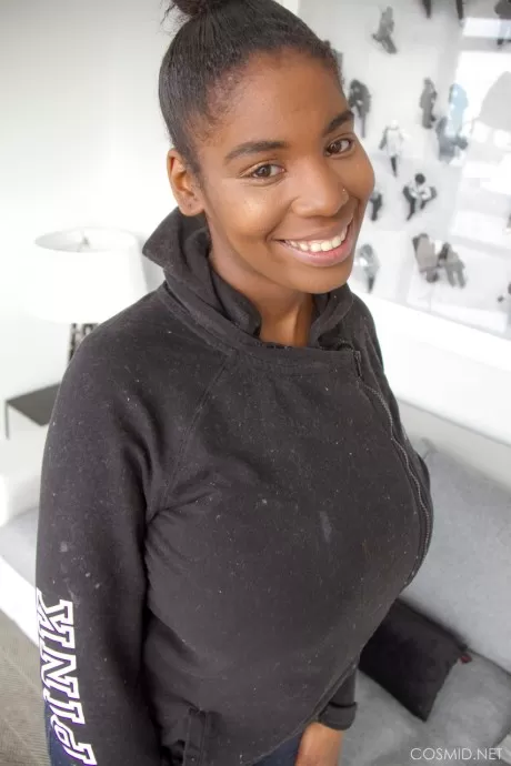 Улыбающаяся негритянка красотка снимает рубашку, чтобы выставить напоказ свои массивные большие сиськи