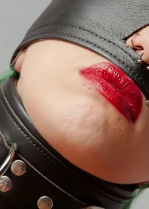 Татуированная женщина с красными губами надела повязку на глаза, будучи связанной