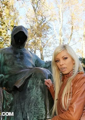 Sexy blonde dons a black leather cape before fucking in the woods