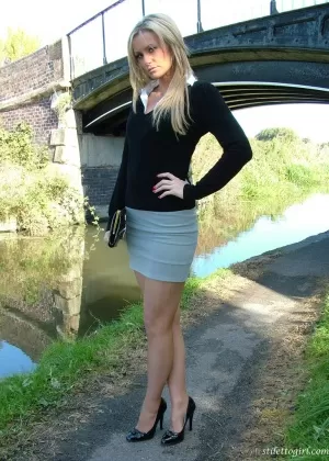 Не обнаженная блондинка демонстрирует сексуальные ноги в мини-юбке и черных лодочках на пешеходной дорожке