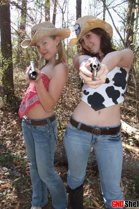 Девушки-лесбиянки обнажают свои сиськи, играя с огнестрельным оружием в лесу