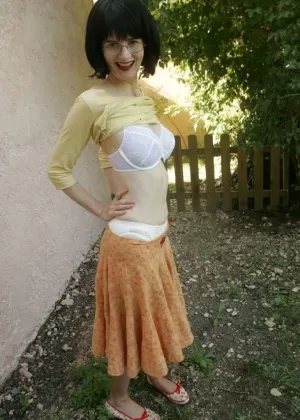 Зрелая брюнетка в чулках снимает с себя платье и верх нижнего белья