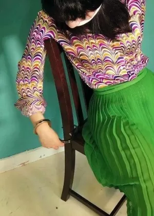 Близкая азиатка снимает наручники на лодыжках после того, как ее приковали к стулу