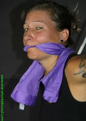 Татуированная девушка клив с кляпом во рту, удерживаемая в неудобной позе